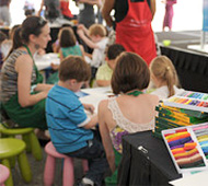 photo of children painting pictures and adults helping