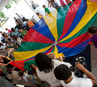 photo of children gathered around a multicolored parachute