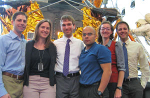 Photo of six men and women standing in front of a space exhibit.