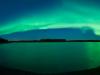 A picturesque lake reflects a beautiful green aurora in North Pole, Alaska.