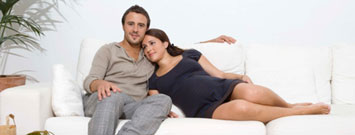 Mujer embarazada y su pareja sentados en un sofá