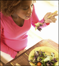Una mujer embarazada comiendo una ensalada