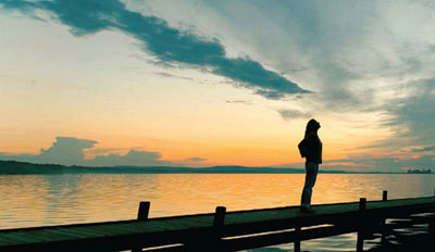 A woman standing on a dock looking at the sky.