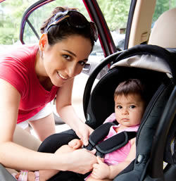 Photo: Mother buckling infant into car seat