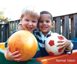 Two young boys holding soccer balls.