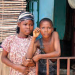 A photograph of two children standing outside a house.