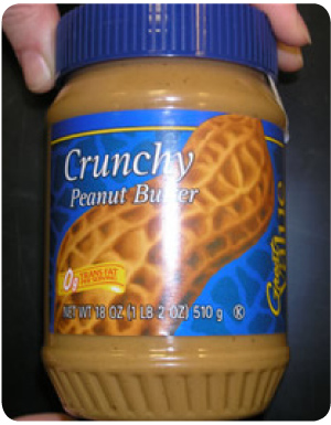 Jar of peanut butter with a blue lid and the front label shown with picture of large peanut and the words Crunchy Peanut Butter