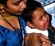 Photo by P. Virot/WHO, Woman holds screaming baby receiving a shot in the arm