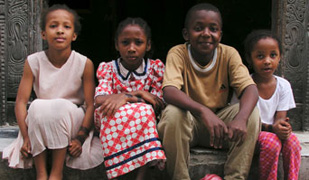 Photo courtesy of World Bank, Four children sit on a doorstep, looking at camera