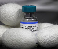 White silk cocoons surround a vial of vaccine