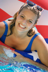 Photo: Woman in pool by American flag, smiling.