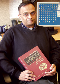 FDA neurologist and medical reviewer Dr. Ranjit Mani, M.D., sitting at his desk holding a neurology text book