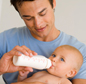 Man feeding infant milk in bottle