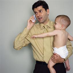 Father holding baby while talking on phone