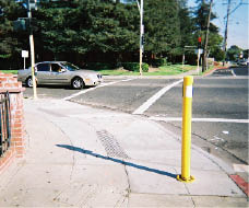 Case Study: Photo of new stub poles – short, small diameter mounts for new pedbuttons –  added at corners of curb ramps at intersection.