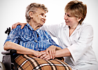 An elderly woman in her wheelchair talks with a nurse