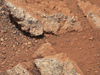 In this image from NASA's Curiosity rover, a rock outcrop called Link pops out from a Martian surface that is elsewhere blanketed by reddish-brown dust. The fractured Link outcrop has blocks of exposed, clean surfaces.