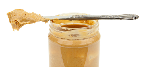 peanut butter jar with knife resting on across the top