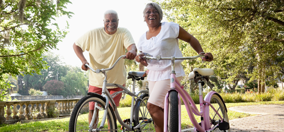 smiling couple holding bicycles in a park