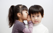 image of a girl whispering into the ear of a boy