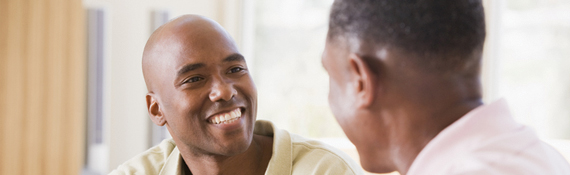 A photo of a man smiling at another man