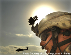 Photograph of a soldier with a helicopter in the sky in the background