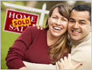 Image of two people standing in front of a sign for a sold home.