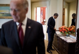 President Barack Obama looks at a magazine on the credenza in the Outer Oval Office before departing the White House for a trip, Sept 27, 2012. Vice President Joe Biden talks with an advisor in the foreground. (Official White House Photo by Chuck Kennedy) 