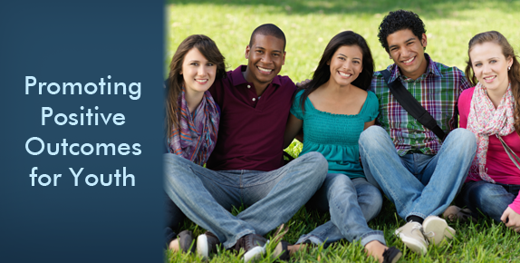 Group of diverse youth sitting together on grass with text to the left Promoting Positive Outcomes for Youth