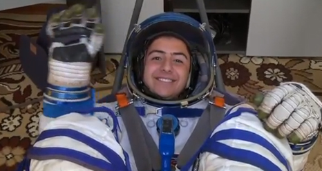 Young man in a Russian spacesuit waves to the camera