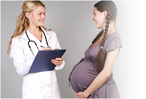 Una mujer embarazada sonrÃ­e mientras la doctora toma nota