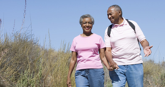 an older couple walking through the dunes, holding hands