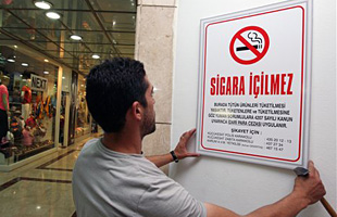 A man hangs a no-smoking sign at the Karum shopping mall in Ankara, Turkey