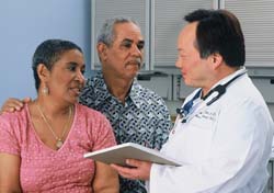 A man and woman speaking with a doctor