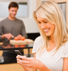 Woman using smart phone in kitchen