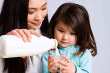 Mother pouring milk for daughter