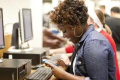 Woman texting while sitting at a computer