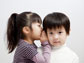 image of a girl whispering into the ear of a boy