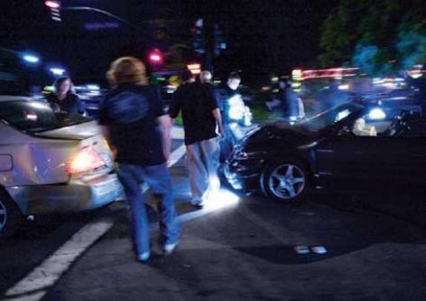 photo of nighttime car crash with teens walking around