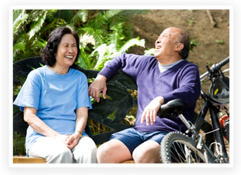 Two young retirees take a break from cycling on a park bench