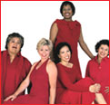 Women of different ethnicities in red dresses and red suits, sitting and standing.