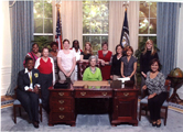 Thirteen women in College Station, Texas, gather in a room resembling the Presidential Oval Office.
