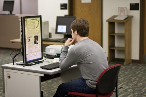 Boy in library using microfiche