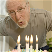 Un hombre viejo soplando las velas de su pastel de cumpleaños