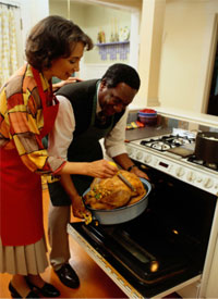 Hombre y mujer midiendo la temperatura de un pavo al horno