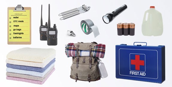 Photograph of disaster supplies, such as walkie-talkies, a flashlight, batteries, a can opener, duct tape, a whistle, bottled water, towels, a backpack, and a first aid kit.