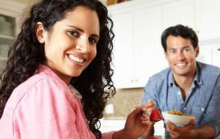 Un hombre y una mujer desayunan cereal con fruta