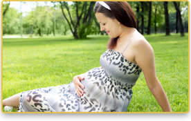 Una mujer embarazada está sentada en el césped y sonríe