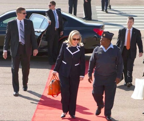 Date: 08/06/2012 Location: Johannesburg, South Africa Description: Diplomatic Security special agents (left, rear center at car, and right) keep watch as U.S. Secretary of State Hillary Rodham Clinton prepares to depart Waterkloof Air Base in Johannesburg, South Africa for a meeting with former South African President Nelson Mandela, August 6, 2012. (AP/Wide World Photos/Jacquelyn Martin, Pool) © AP Image