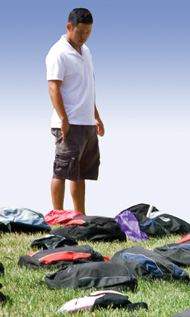 photo of a man looking down at several backpacks arranged on the grass